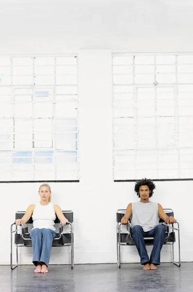 Couple sitting on separate chairs — Stock Photo, Image