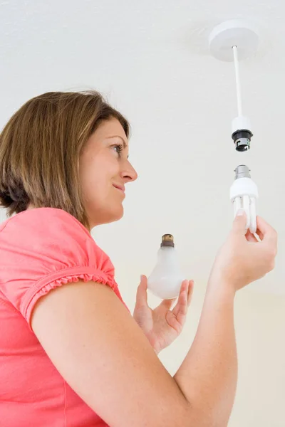 A young woman changing her lightbulb