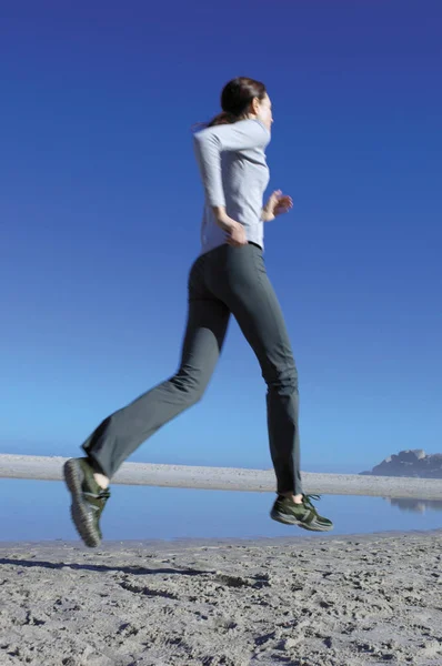 Жінка біжить на пляжі — стокове фото
