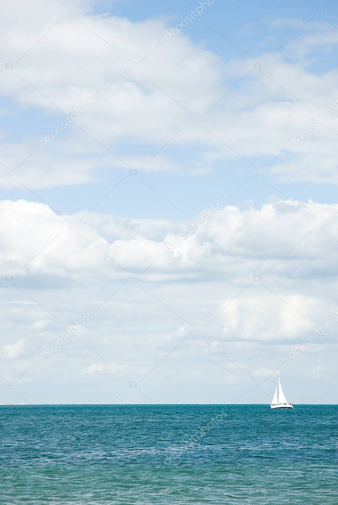Sailboat on sea surface with cloudy sky on background