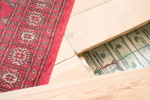 Close up view of carpet and hidden money under wooden floorboards