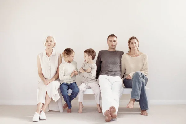 Famille Assise Dans Une Rangée Isolée Sur Fond Blanc — Photo