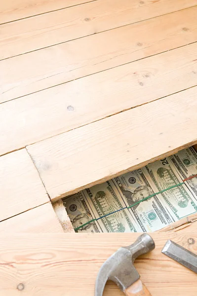 Close up view of hidden money under wooden floorboards and hammer