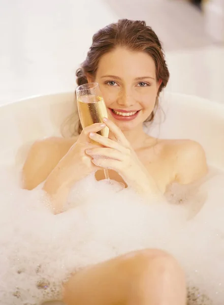 Vrouw liggend in een bad met glas champagne — Stockfoto