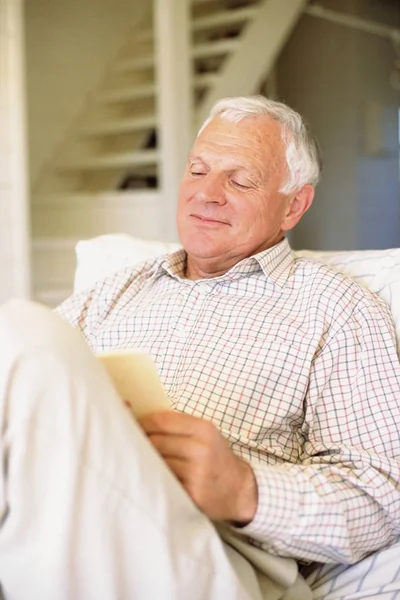 Uśmiechający Się Starszy Człowiek Siedzi Czytanie Książki — Zdjęcie stockowe