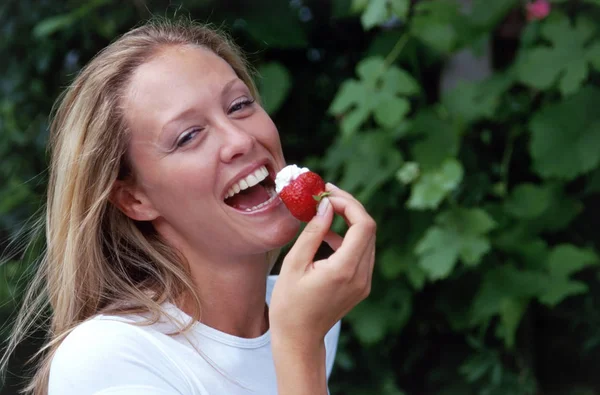 Flicka äter jordgubbar i trädgården — Stockfoto