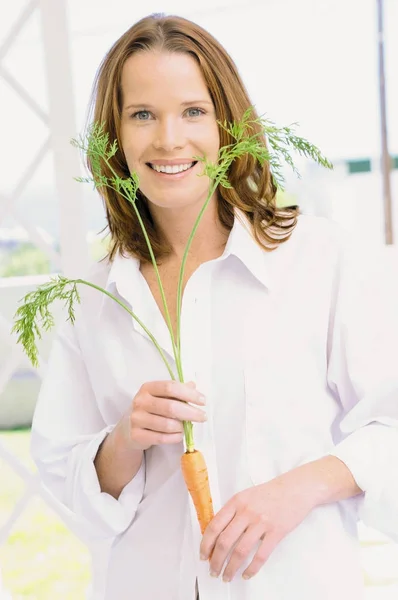Wanita tersenyum memegang wortel — Stok Foto