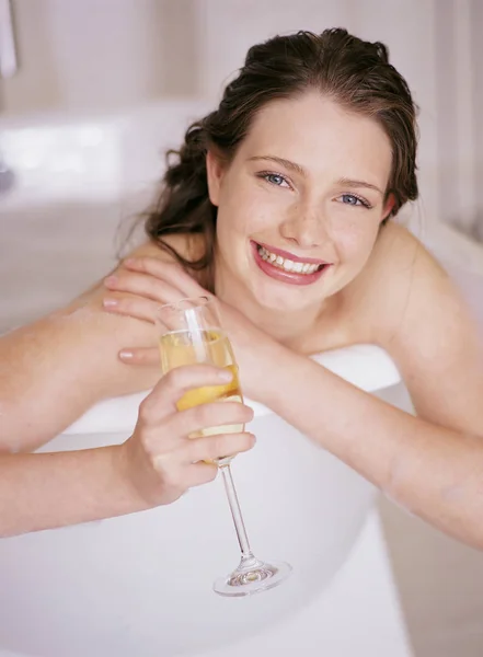 Жінка лежить у ванні і тримає келих шампанського — стокове фото