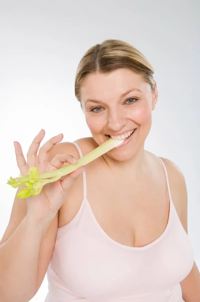 Sobrepeso Caucasiano Mulher Comer Aipo Contra Fundo Cinza — Fotografia de Stock