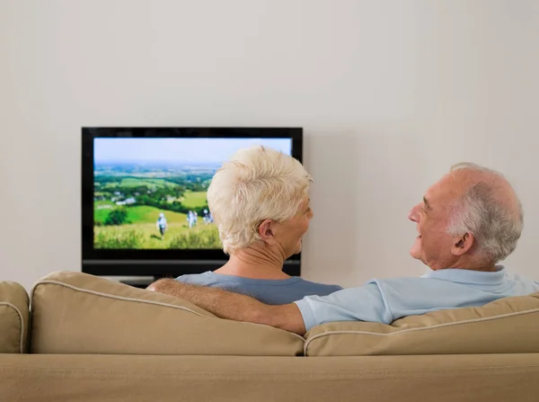 先輩夫婦がテレビを見て話してる — ストック写真