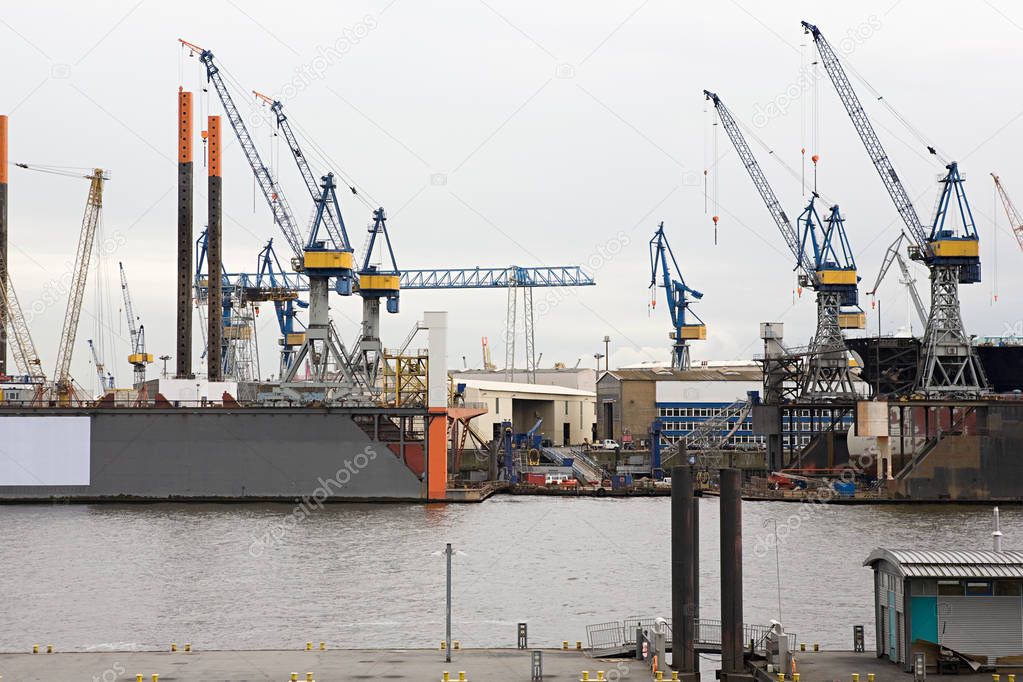 Front view of Hamburg harbor with cranes under rainy clouds