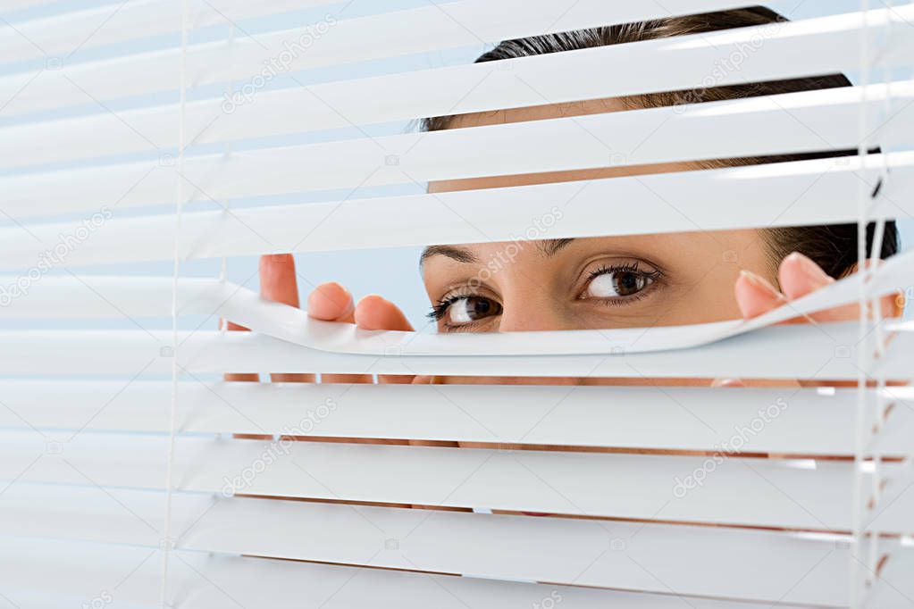 Woman looking though blinds