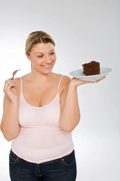 Толстая Белая Женщина Держит Шоколадный Торт Сером Фоне — стоковое фото