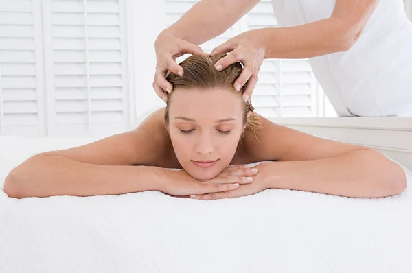 young blond caucasian woman having head massage in spa