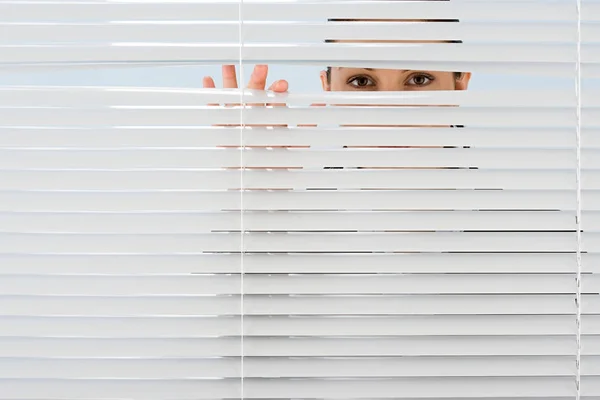 Vrouw Kijkt Door Blinds — Stockfoto