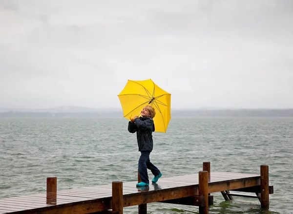 ウッドデッキに傘を運ぶ少年 — ストック写真