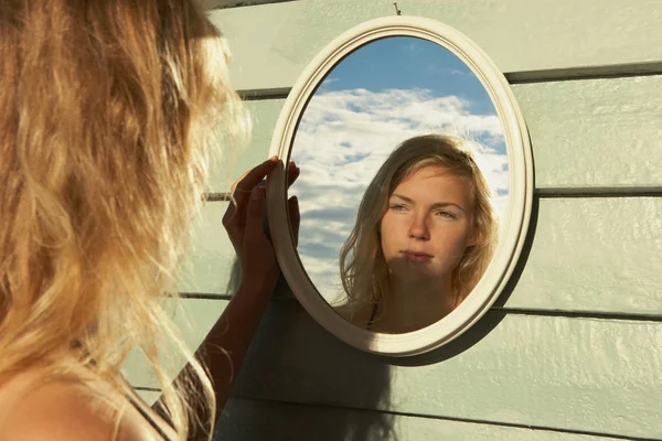 Young Woman Looking in Mirror outside