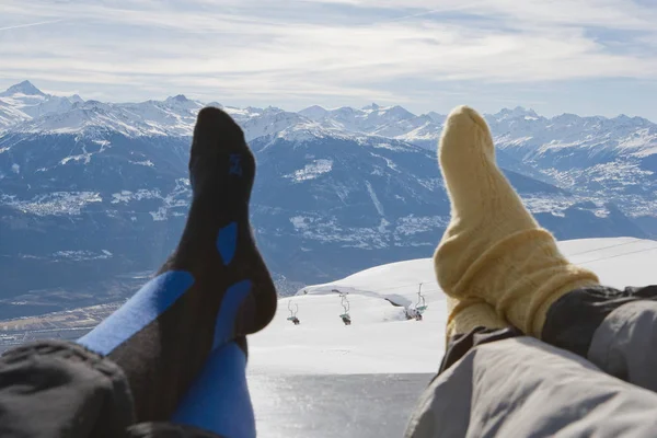 cropped image of resting feet on bench with mountain view