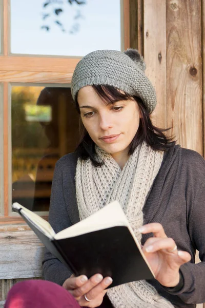 美丽的年轻白种女人在门廊阅读书 — 图库照片