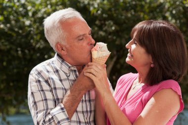 Older caucasian couple sharing ice cream cone clipart
