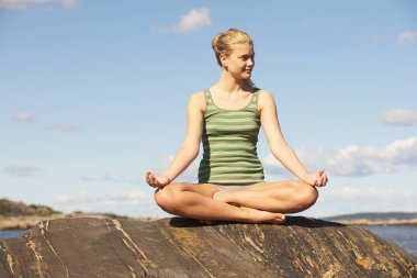 Young Woman doing Yoga on rocks clipart