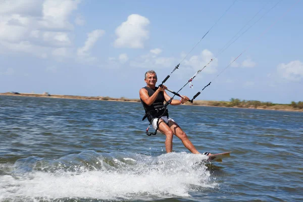 Older man wind surfing on lake