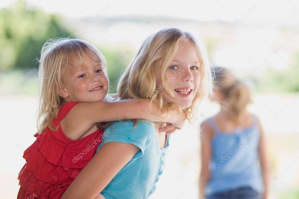 Girl carrying younger sister piggyback