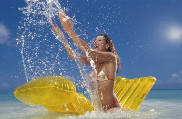 mid adult beautiful caucasian woman in bikini on air mattress making water splashes