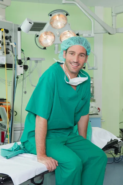 Lächelnder Chirurg Sitzt Auf Dem Operationstisch Und Blickt Die Kamera — Stockfoto