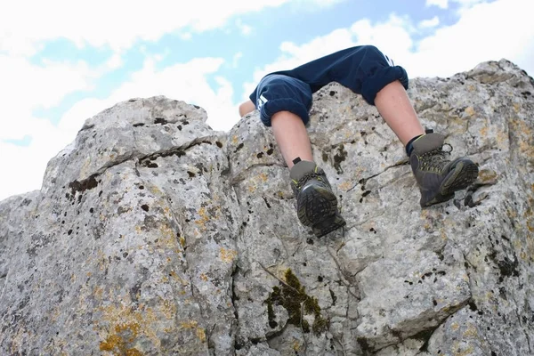 Низкий Угол Зрения Мальчика Сидящего Скалистой Скале Против Голубого Облачного — стоковое фото