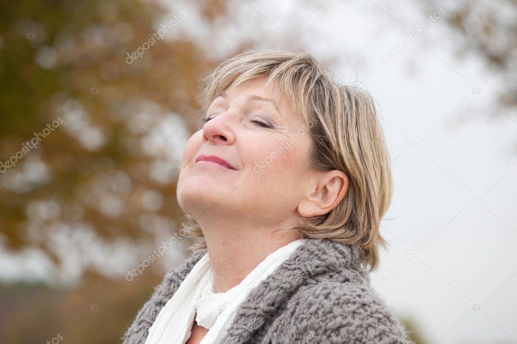 portrait of older woman relaxing outdoors in autumn