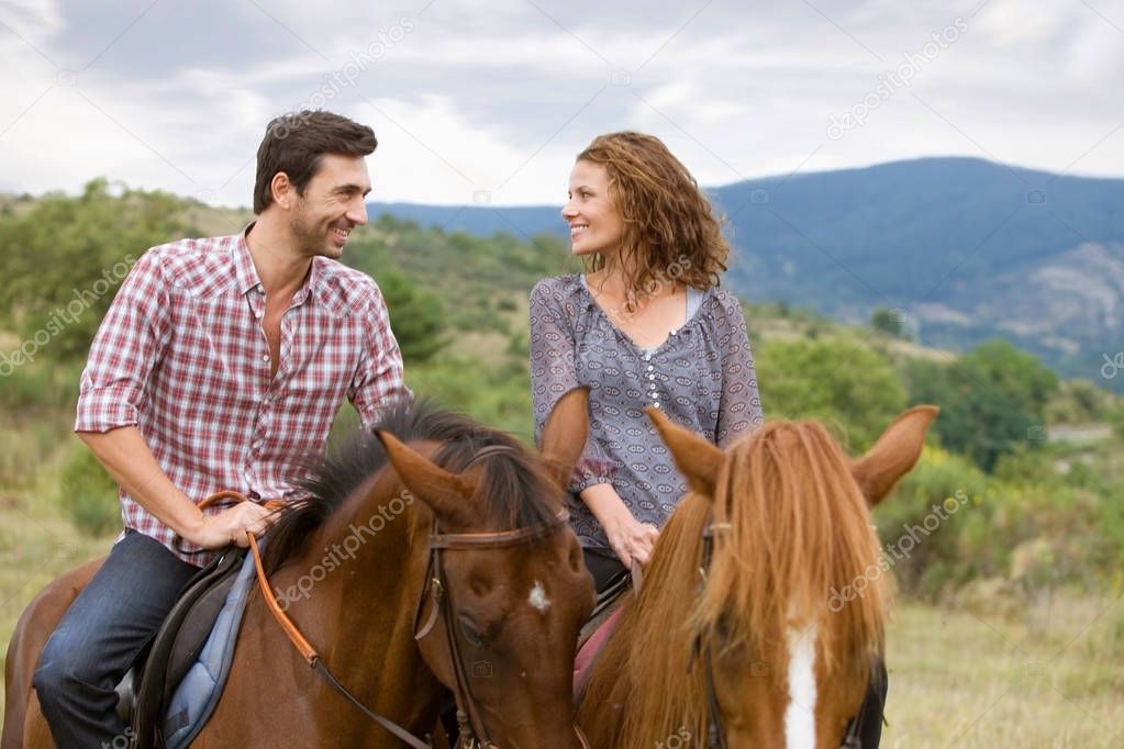 Couple riding horses in mountains 
