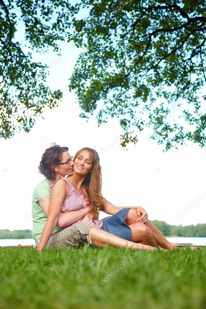 adult caucasian homosexual couple of women cuddling in park