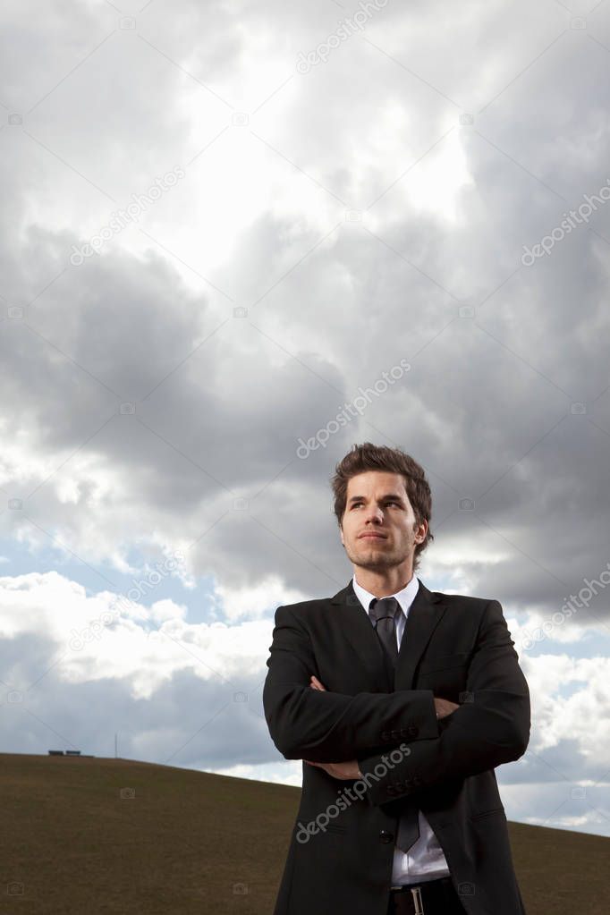 successful caucasian businessman posing against cloudy sky
