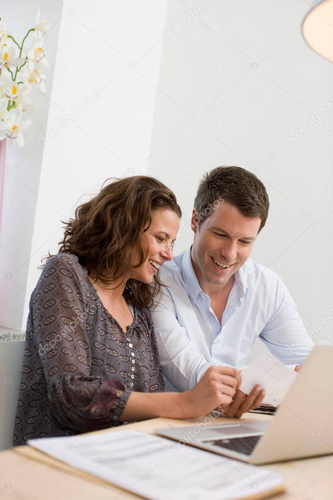 adult caucasian couple using laptop together at home