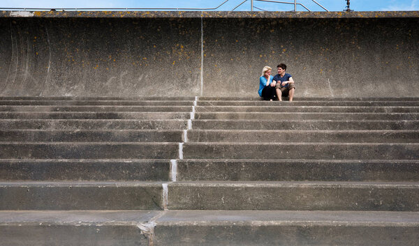 young pretty caucasian couple sitting together on steps
