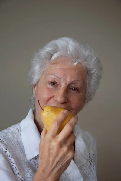 Senior Kaukasisk Kvinna Äta Päron Mot Beige Bakgrund — Stockfoto