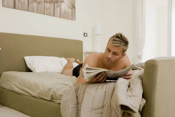 Νεαρός Άνδρας Διαβάζοντας Εφημερίδα Στο Κρεβάτι — Φωτογραφία Αρχείου