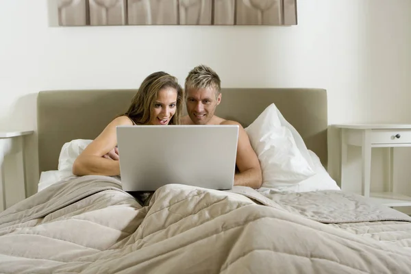 ベッドでノートパソコンを使う若いカップル — ストック写真