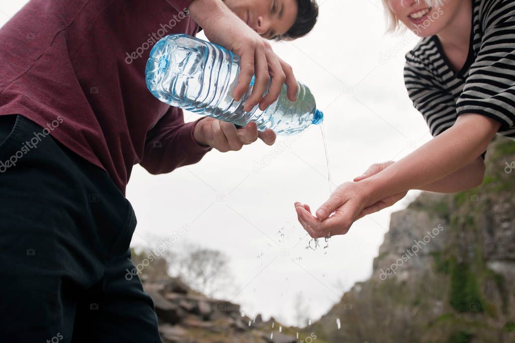 young pretty caucasian man pouring water into womans hands