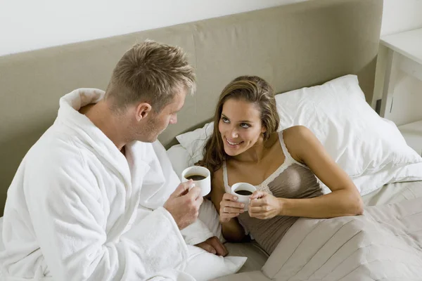 若いカップル ベッドの中でコーヒーを飲む — ストック写真