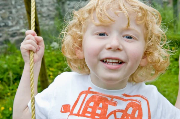 スイングに笑みを浮かべて少年 — ストック写真