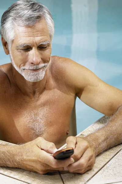 在游泳池里拿手机的男人 — 图库照片