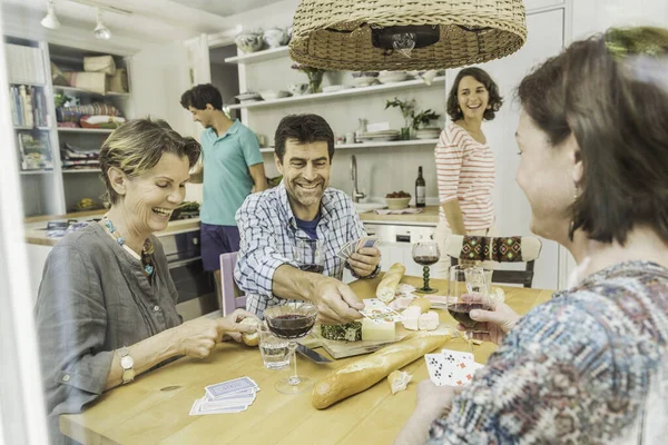 Пять взрослых друзей играют в карты за обеденным столом — стоковое фото