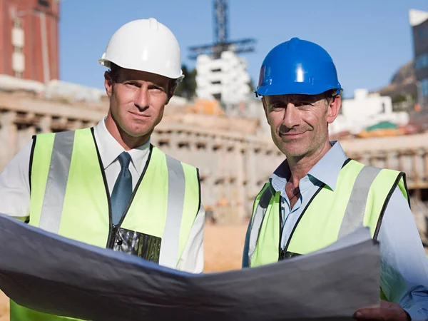 stock image Mature men with blueprint on construction site