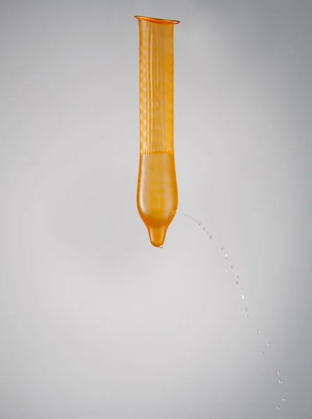 有液体渗漏的橙色避孕套 — 图库照片