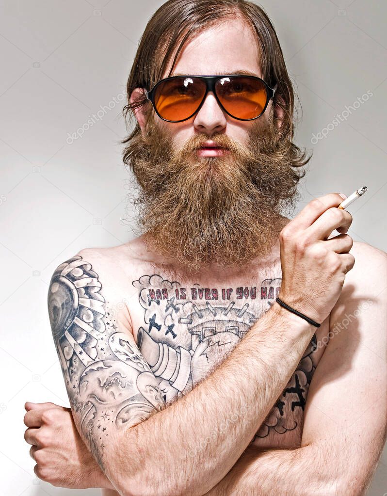 Portrait of young man with tattoos smoking cigarette in studio 