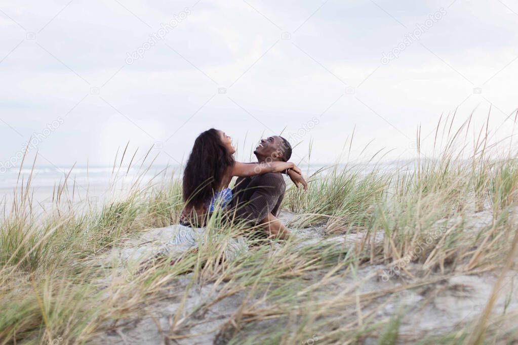 Couple fooling around in sand dunes, laughing