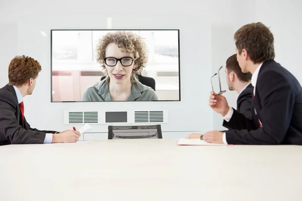 Zakenmensen Zitten Rond Vergadertafel Met Video Conferentie Met Vrouw — Stockfoto