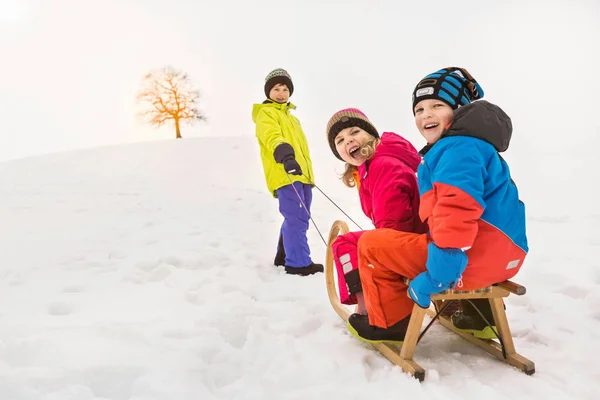 Boy Empujando Dos Amigos Través Nieve Tobogán —  Fotos de Stock